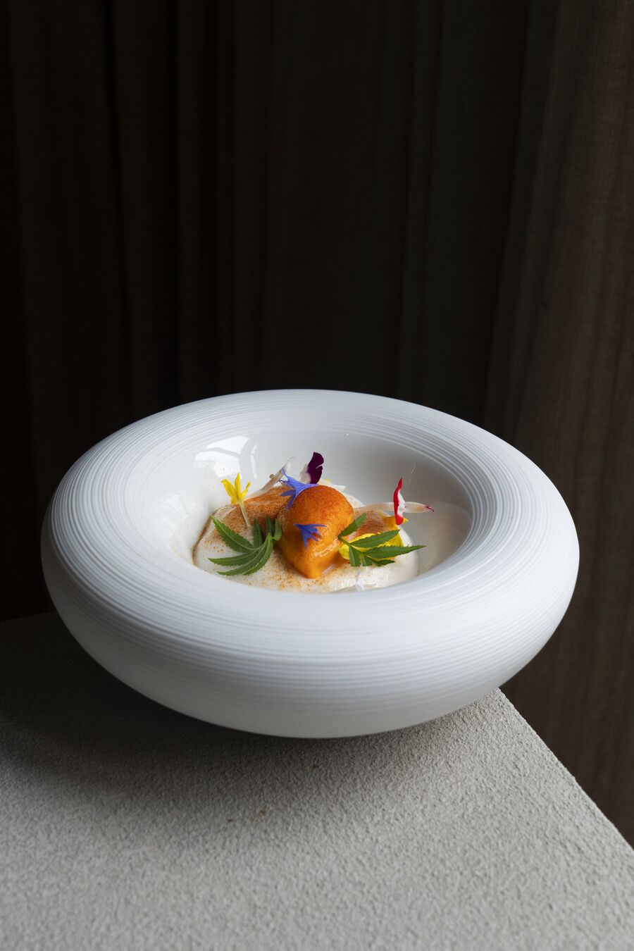 Gerecht met eetbare bloemen in een ronde witte schaal