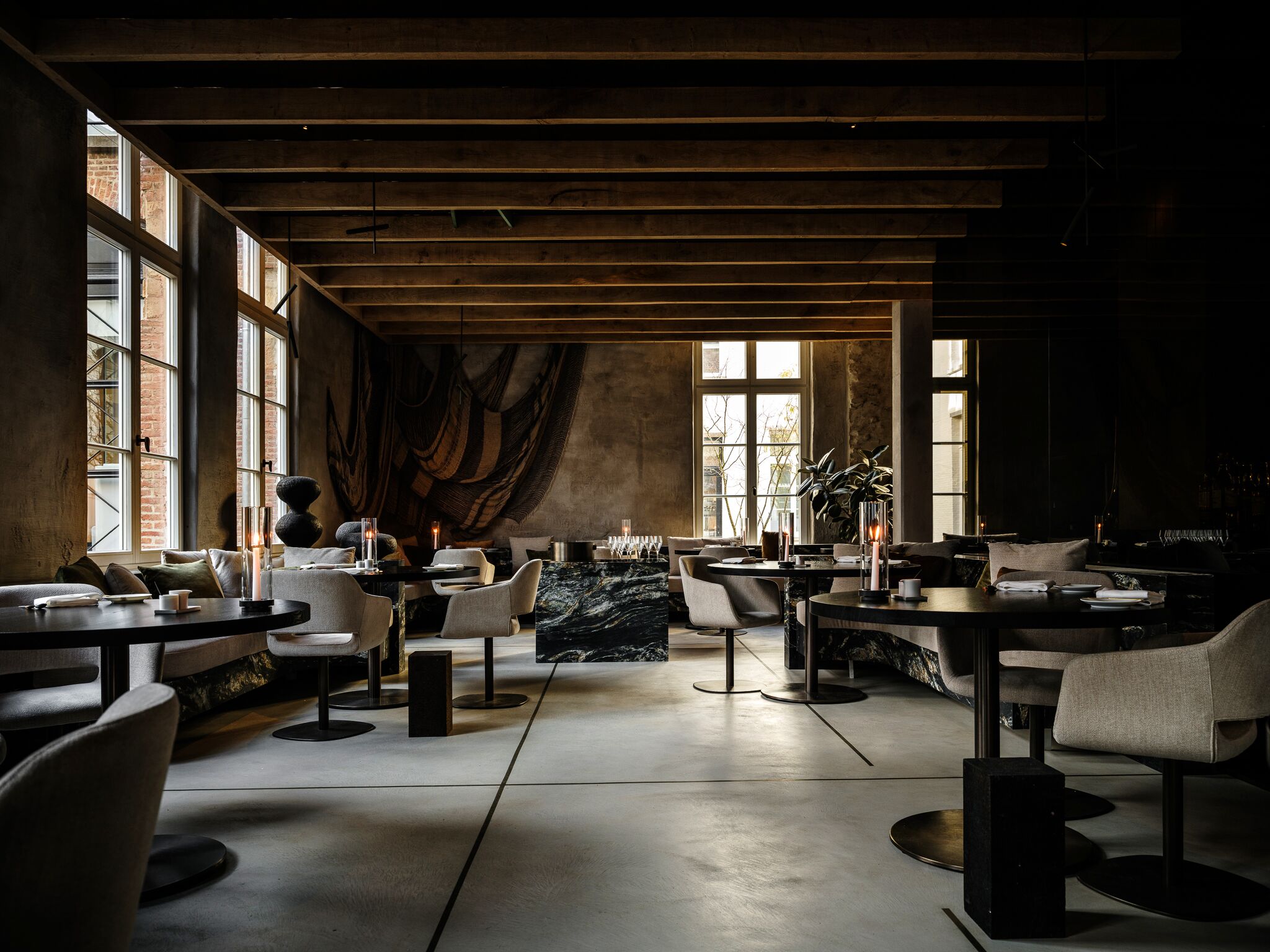 De eetzaal van Fine Fleur met eiken balken, hoge ramen en ronde tafels